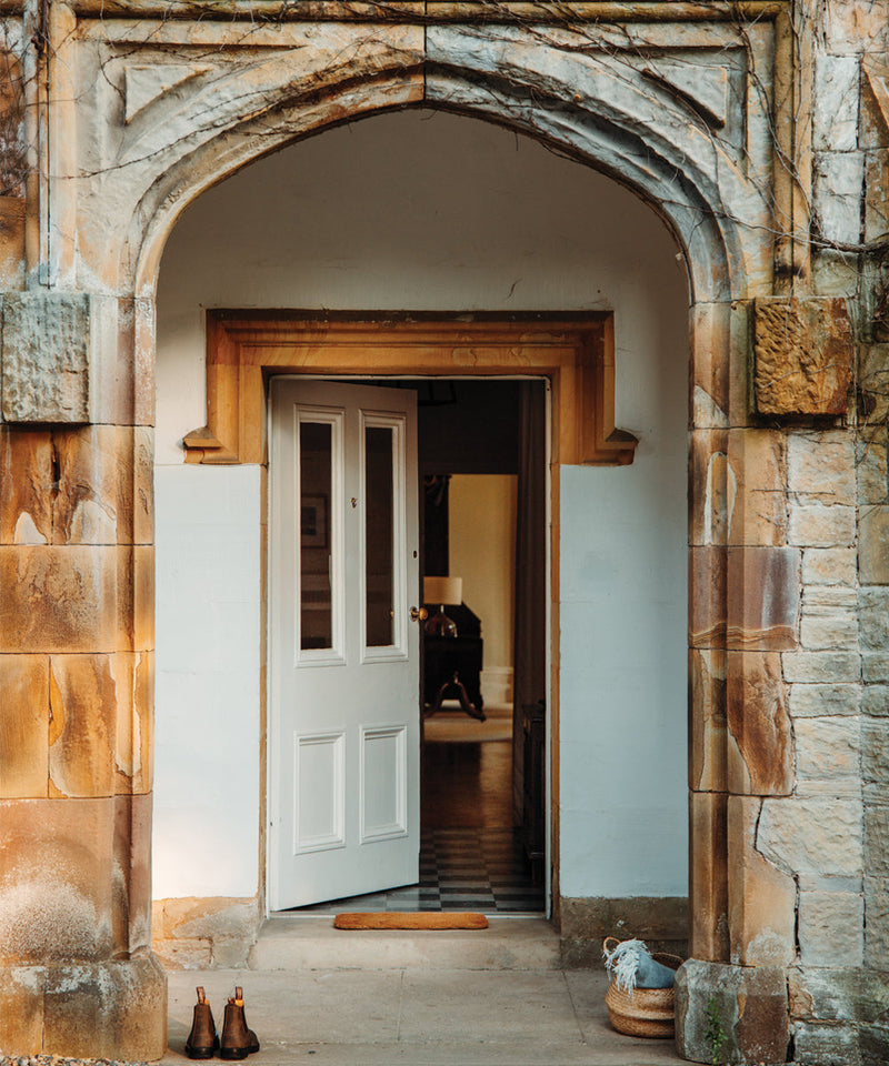 Historic stone entrance with an arched doorway leading into a traditional countryside home