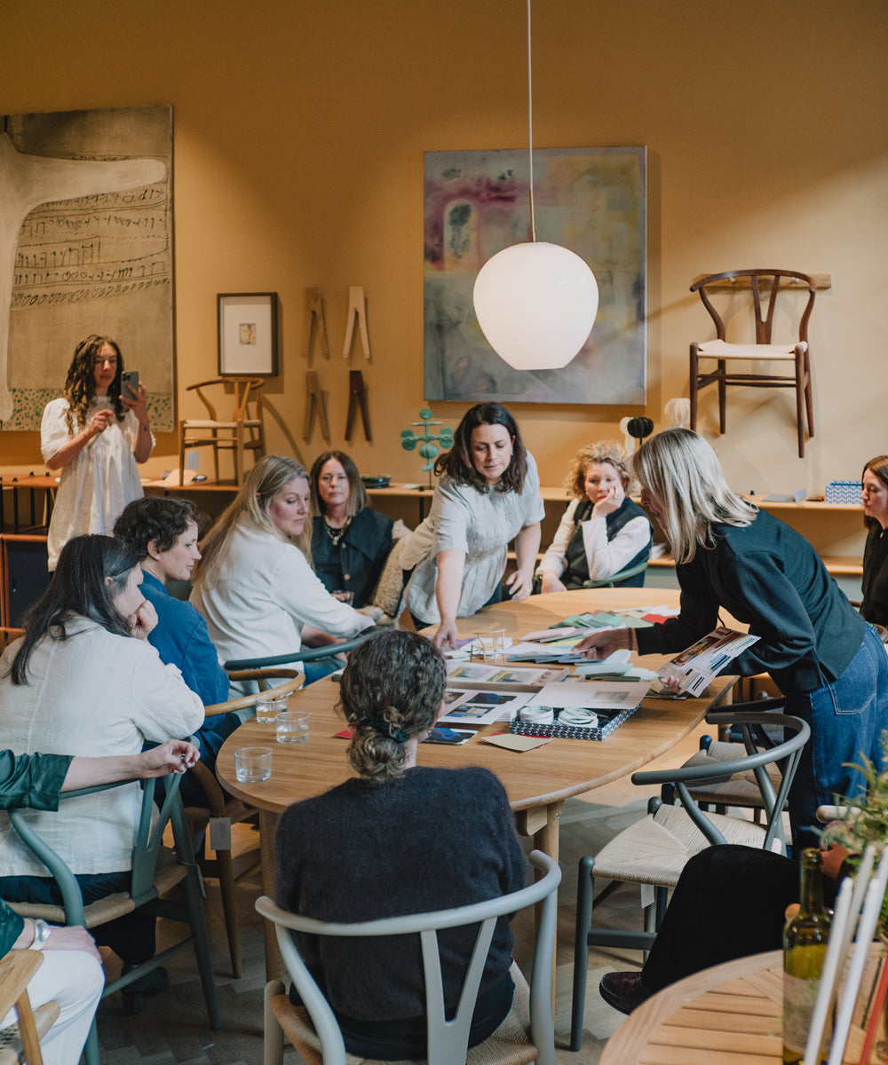 A group gathered around a table with two people giving instructions about the colour workshop they are about to undertake 