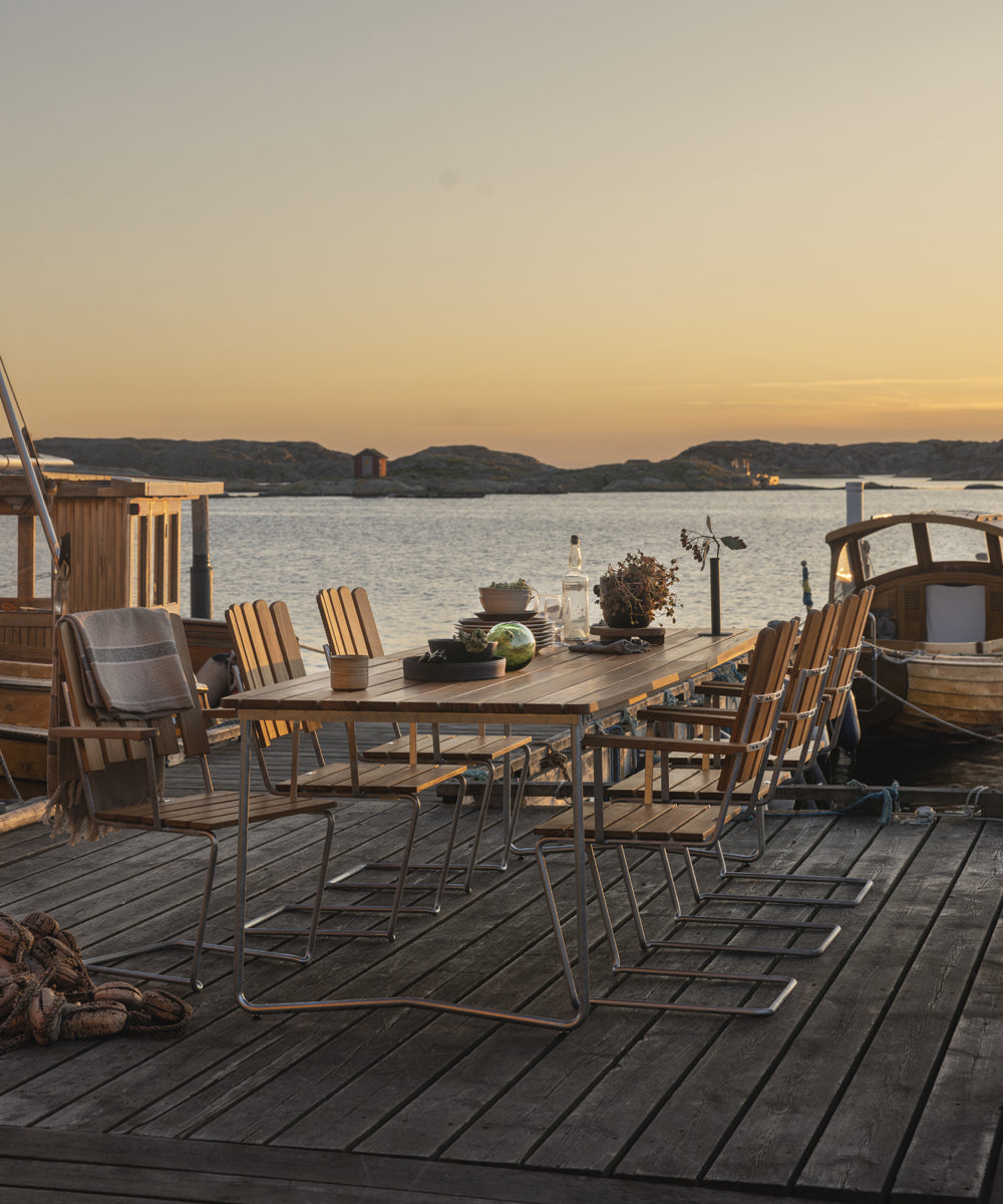 A collection of outdoor furniture by Grythyttan Stalmobler on a wooden deck next to the sea