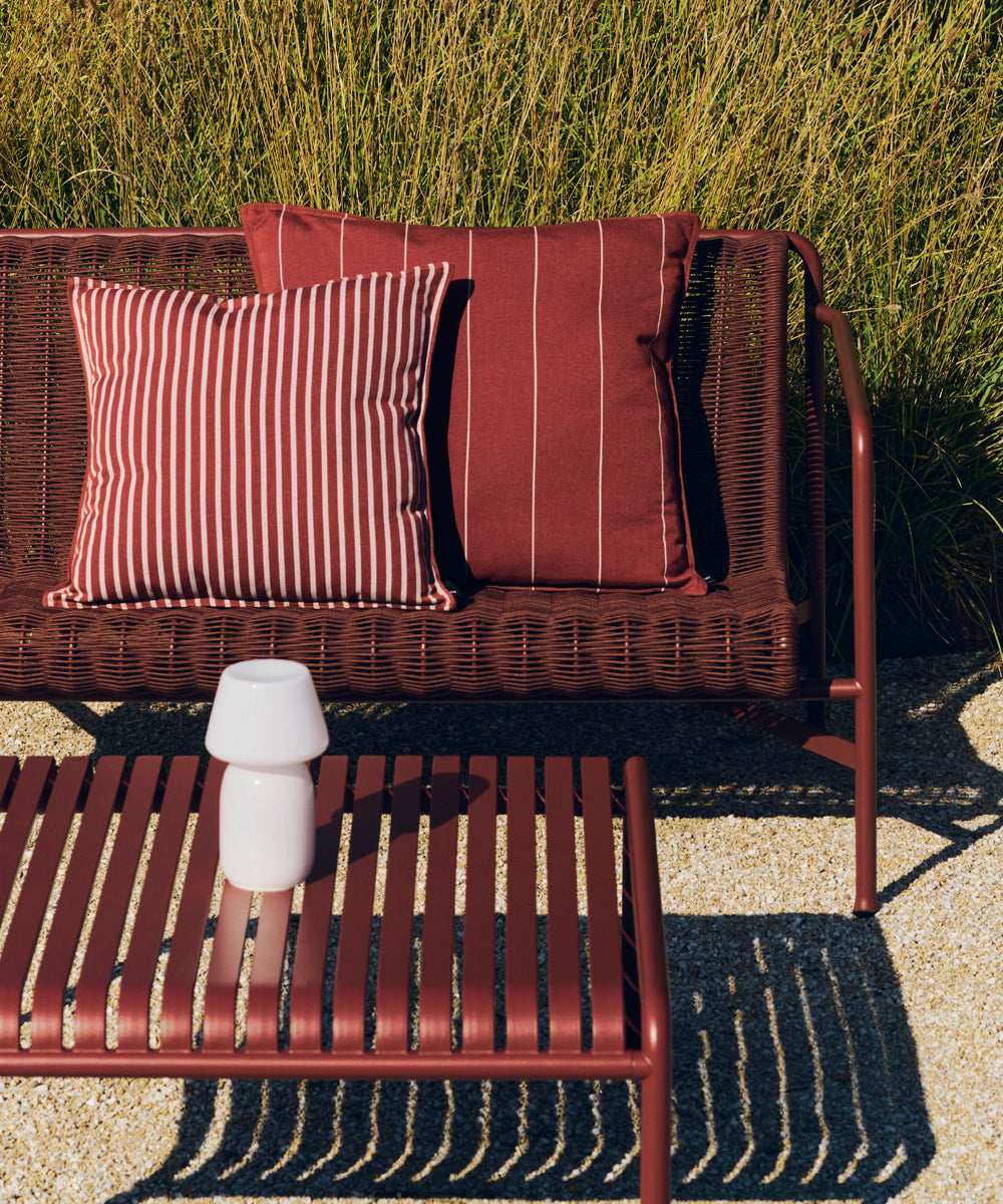 Featuring a collection of outdoor furniture from the HAY Palissade range, all finished in an iron red colour