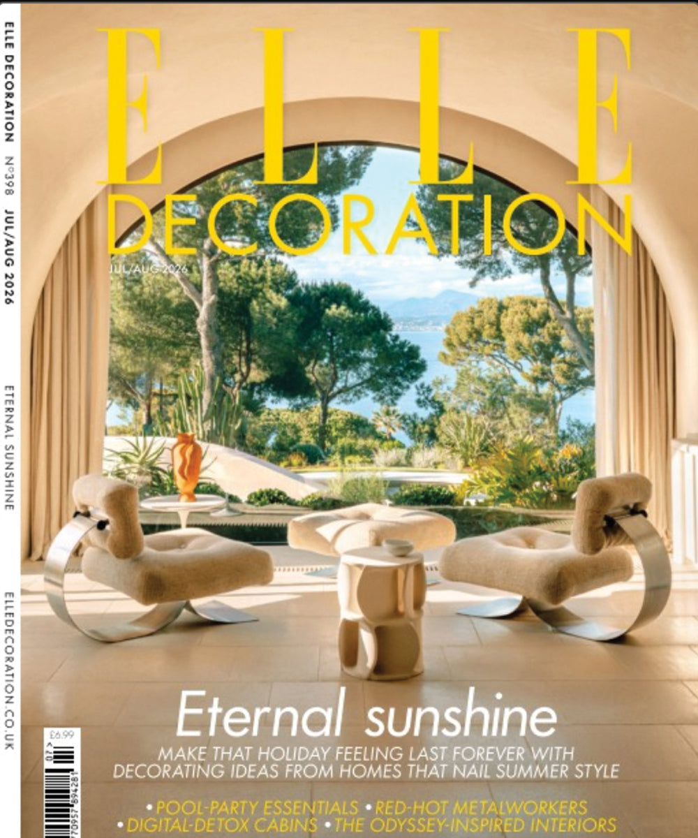 ELLE Decoration magazine cover featuring a sunlit Mediterranean-style interior with sculptural lounge chairs, a curved archway, and a lush garden view overlooking the sea.